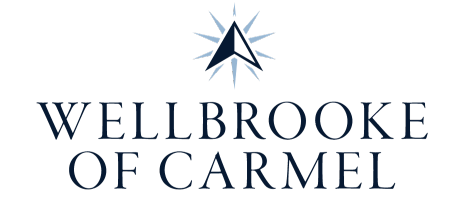 Wellbrooke of Carmel logo featuring a navy starburst emblem above the blue wordmark
